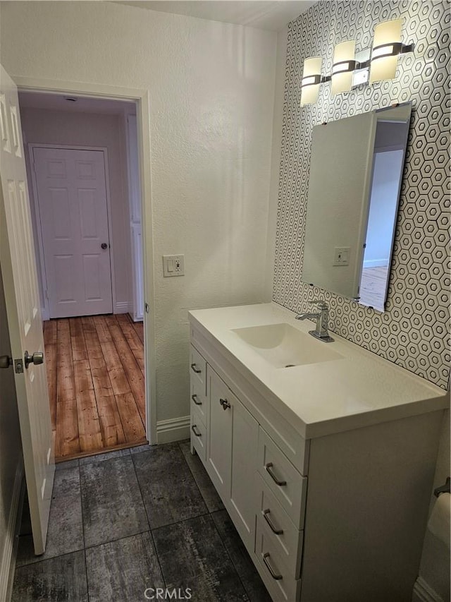 bathroom featuring vanity, baseboards, and a textured wall