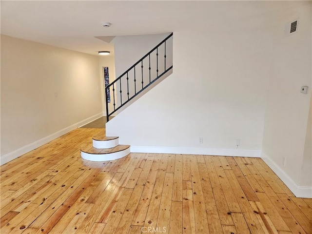 staircase with visible vents, wood-type flooring, and baseboards