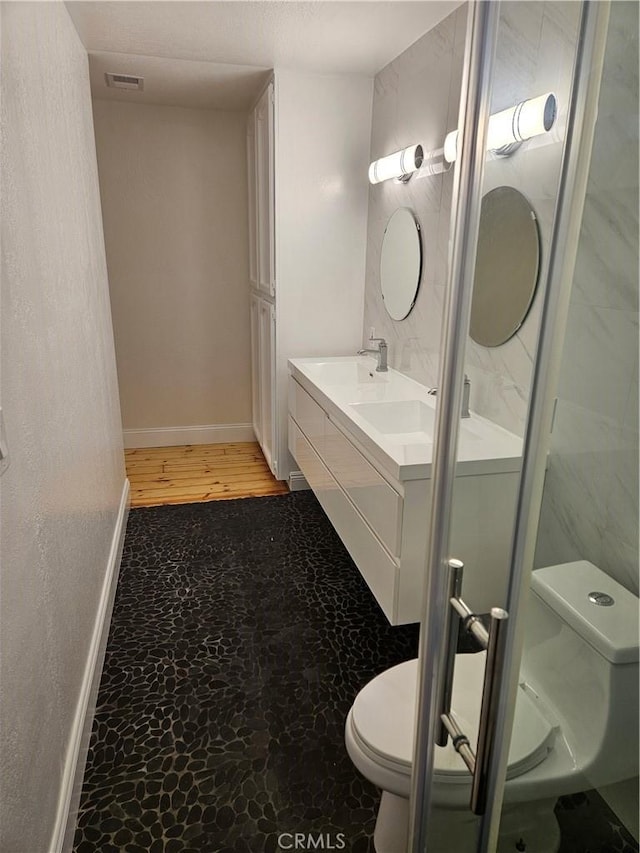 full bathroom featuring visible vents, toilet, baseboards, and double vanity