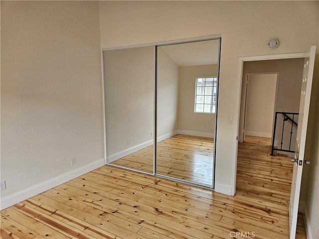 unfurnished bedroom featuring a closet, baseboards, and hardwood / wood-style flooring