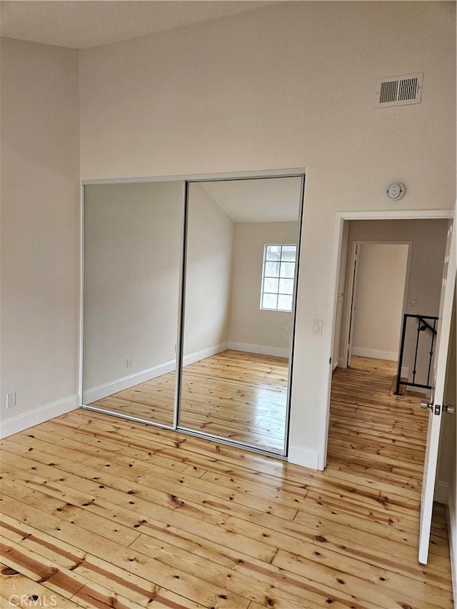 unfurnished bedroom featuring light wood-type flooring, visible vents, baseboards, and a closet