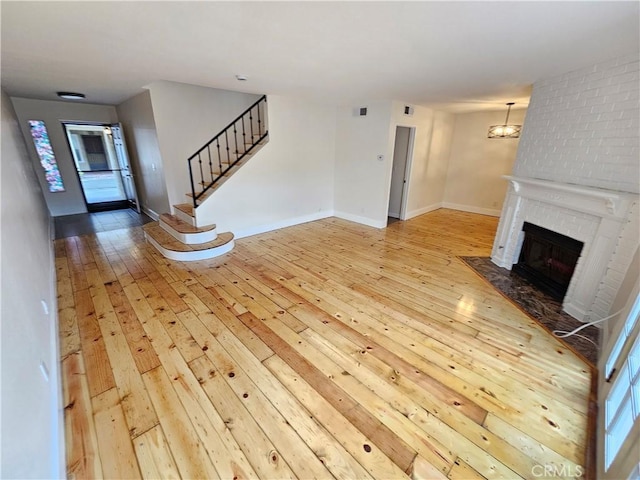 unfurnished living room featuring stairway, a fireplace, baseboards, and hardwood / wood-style flooring