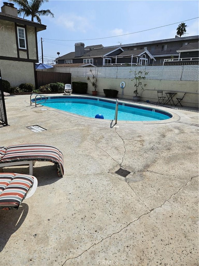 community pool with a patio and fence private yard