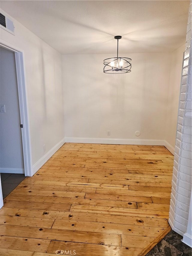 unfurnished dining area with hardwood / wood-style flooring, baseboards, and visible vents