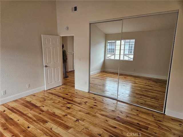 unfurnished bedroom with a closet, visible vents, baseboards, and hardwood / wood-style floors