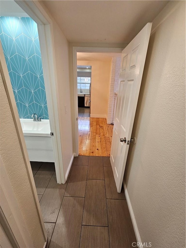 hall featuring a sink, baseboards, and wood tiled floor