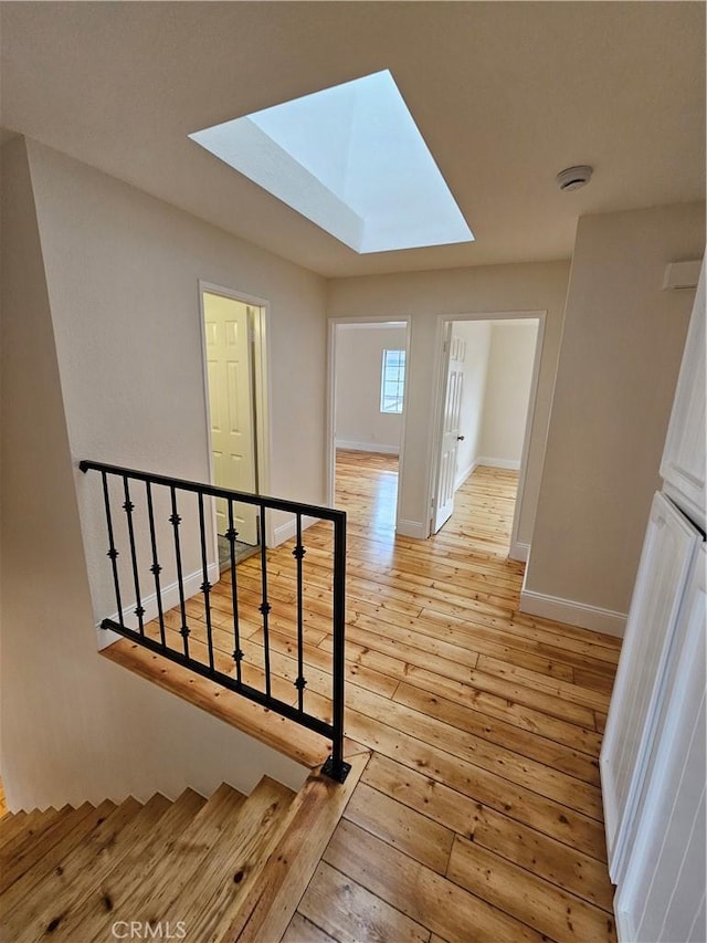 staircase featuring hardwood / wood-style floors, baseboards, and a skylight