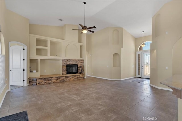 unfurnished living room with built in features, ceiling fan, tile patterned flooring, high vaulted ceiling, and a fireplace