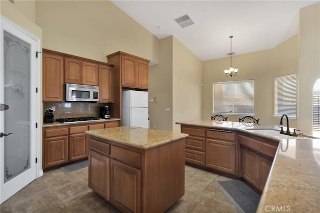 kitchen featuring appliances with stainless steel finishes, tasteful backsplash, sink, hanging light fixtures, and a center island