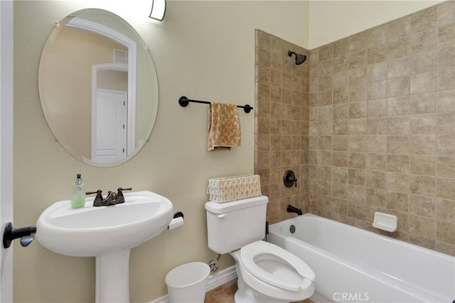 bathroom featuring tiled shower / bath combo and toilet