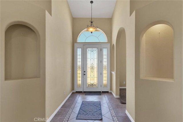 entrance foyer featuring a towering ceiling and tile patterned flooring