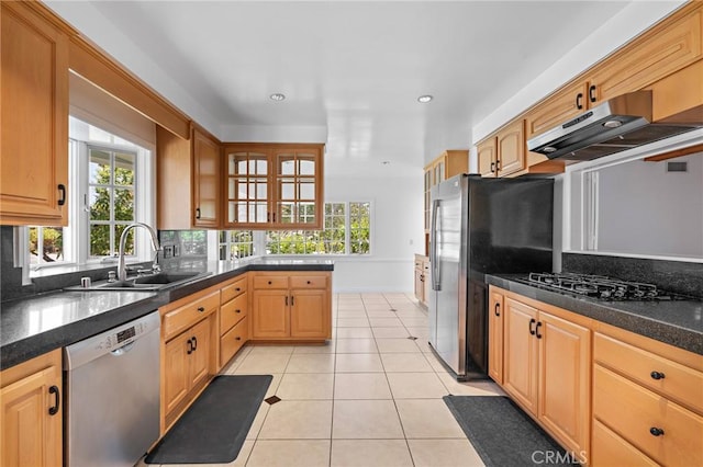 kitchen with light tile patterned floors, stainless steel appliances, dark stone counters, and sink