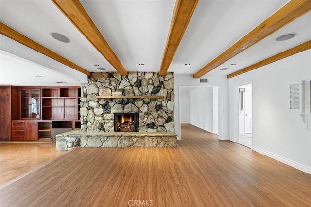 unfurnished living room with beam ceiling, wood-type flooring, and a fireplace