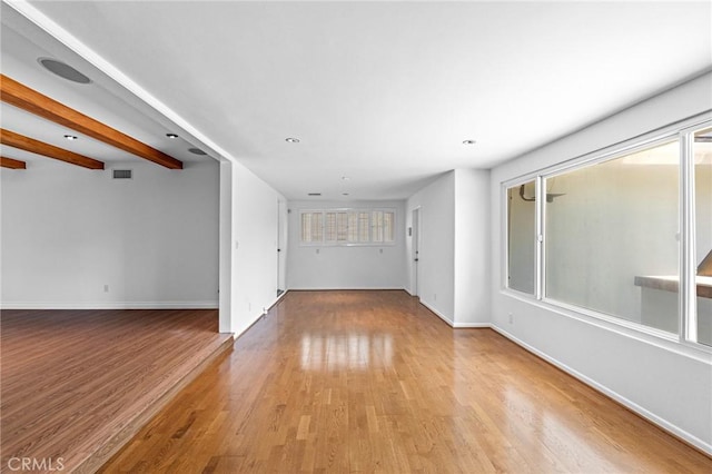 unfurnished living room featuring light hardwood / wood-style floors and beam ceiling