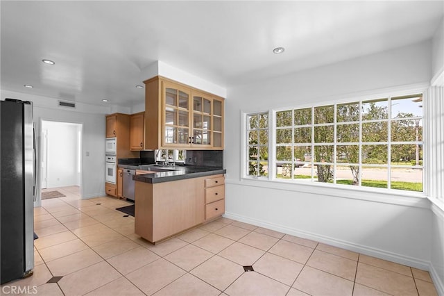 kitchen with plenty of natural light, sink, light tile patterned floors, and stainless steel appliances