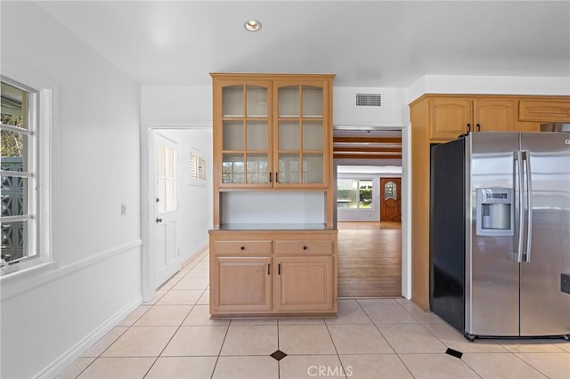 kitchen with light tile patterned flooring, stainless steel fridge with ice dispenser, and a wealth of natural light