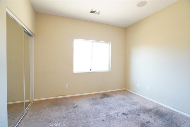 unfurnished bedroom with carpet, a closet, visible vents, and baseboards