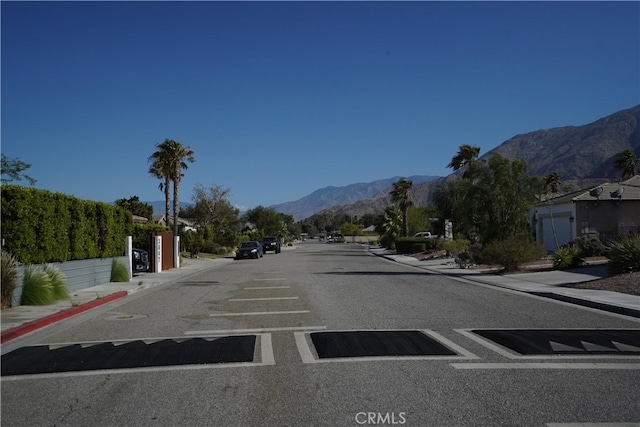 view of street with curbs, a mountain view, and sidewalks