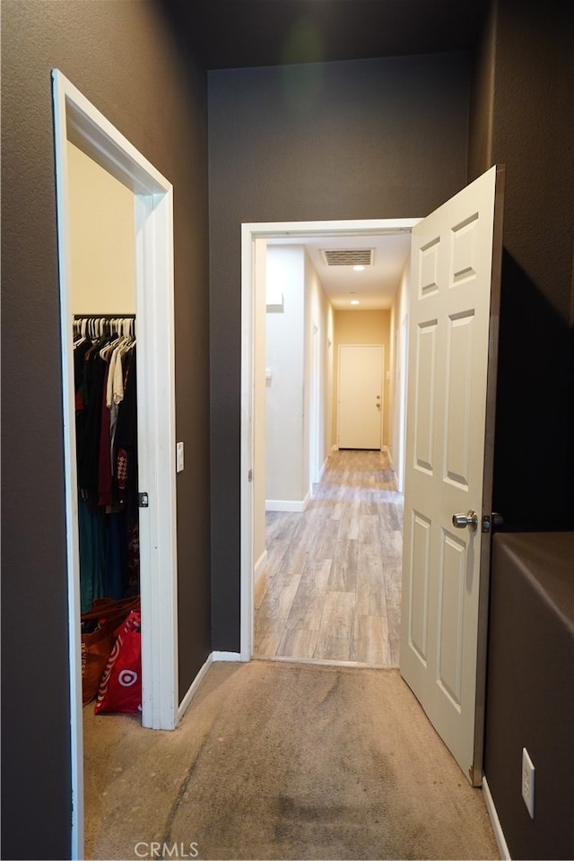 hallway featuring carpet floors, visible vents, and baseboards