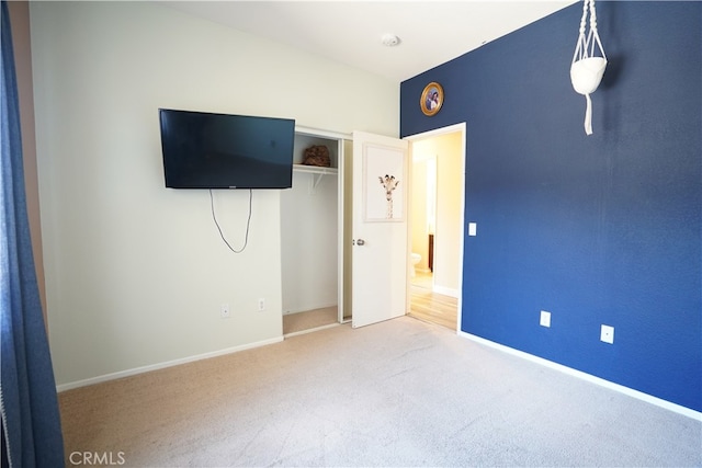 unfurnished bedroom with carpet, a closet, and baseboards