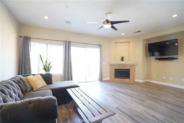 living area with dark wood-style floors, baseboards, visible vents, and a tiled fireplace