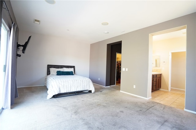 bedroom featuring a walk in closet, light carpet, visible vents, and baseboards