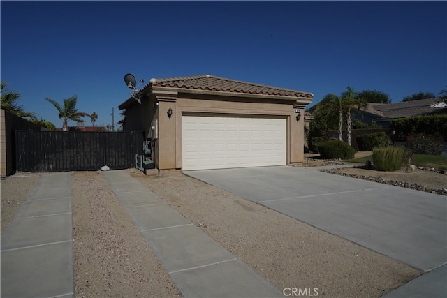 view of home's exterior with stucco siding, fence, a garage, driveway, and a tiled roof