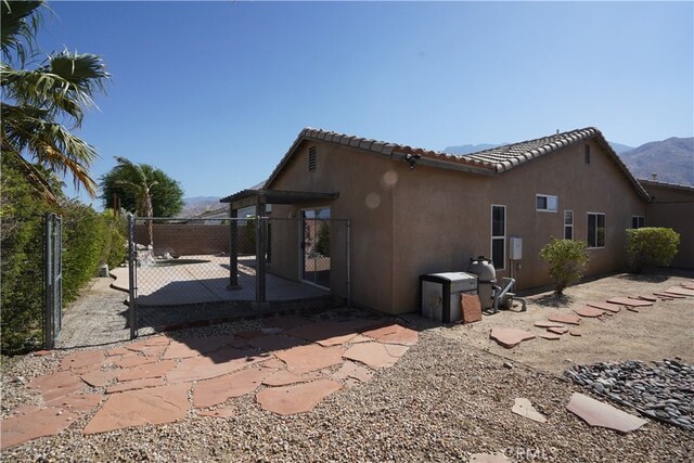 view of home's exterior featuring a mountain view, fence, a tiled roof, stucco siding, and a patio area