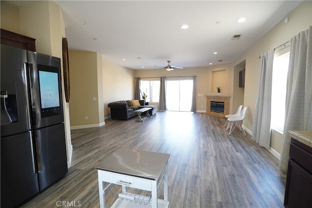 living room with a tile fireplace, recessed lighting, wood finished floors, visible vents, and baseboards