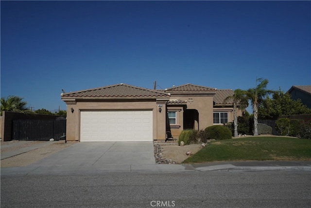 mediterranean / spanish home featuring a garage, fence, a tiled roof, concrete driveway, and stucco siding