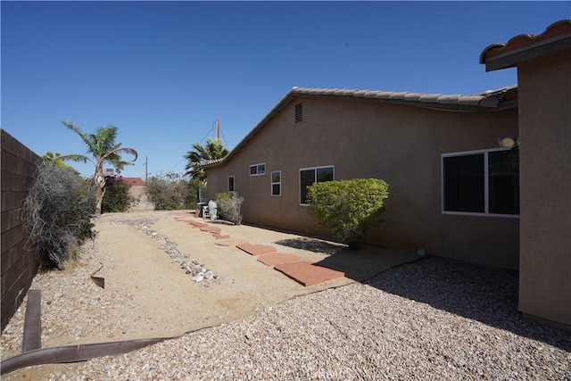 view of side of home featuring a tile roof, a patio area, a fenced backyard, and stucco siding