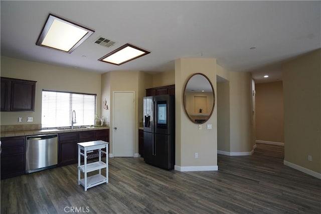 kitchen with visible vents, dishwasher, tile countertops, black fridge, and a sink