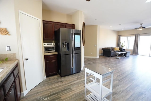 kitchen with dark brown cabinetry, light wood finished floors, stainless steel fridge, ceiling fan, and light countertops