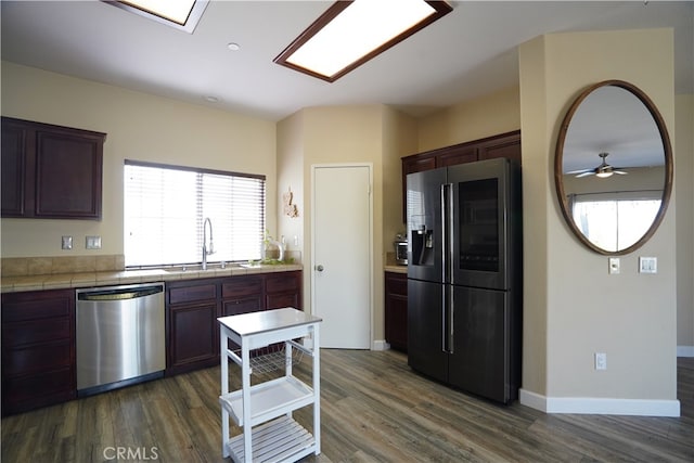 kitchen with baseboards, tile countertops, dark wood-style floors, appliances with stainless steel finishes, and a sink