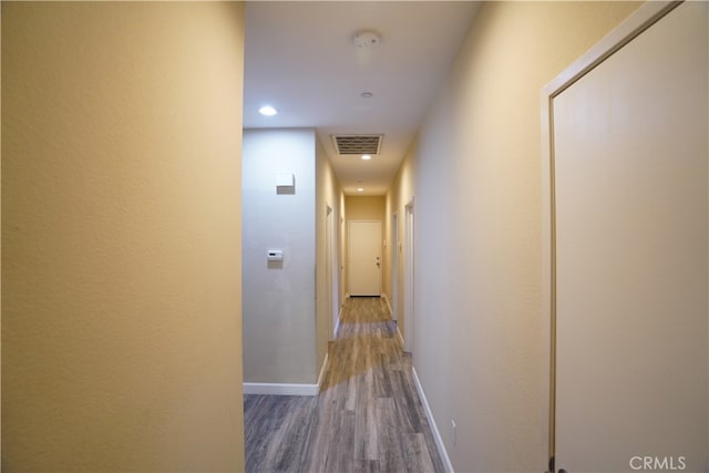 hall with wood finished floors, visible vents, and baseboards