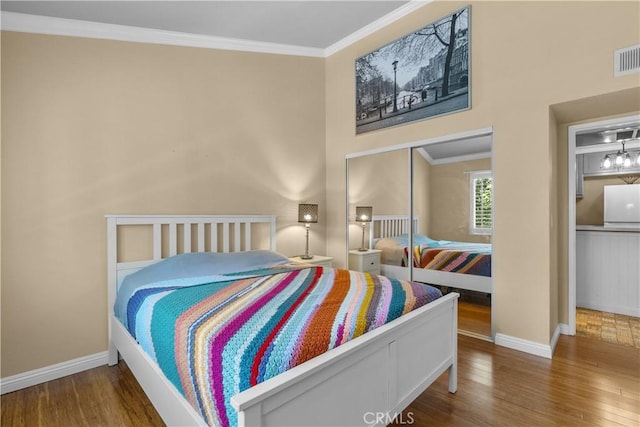 bedroom with hardwood / wood-style flooring, a closet, crown molding, and white fridge