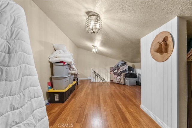 bonus room featuring hardwood / wood-style floors, a textured ceiling, and vaulted ceiling