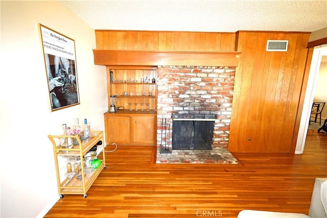 622 E Lomita Ave, Orange, CA 92867 - living area featuring a textured ceiling, visible vents, wood finished floors, wooden walls, and a fireplace