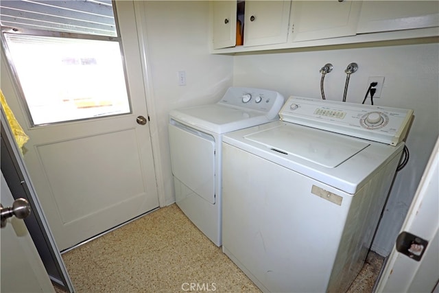 clothes washing area featuring cabinets and washer and dryer