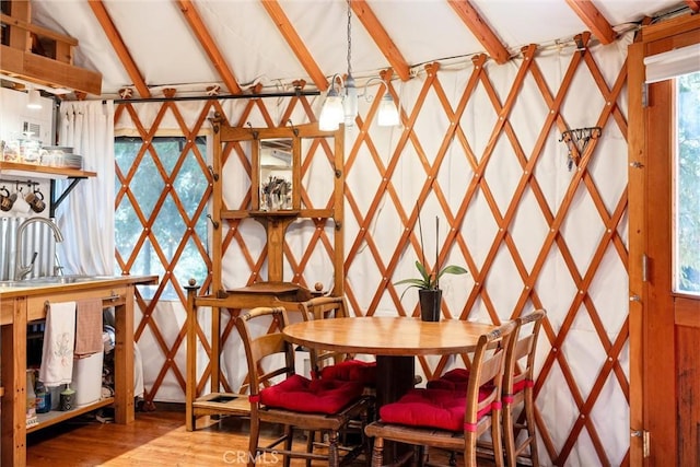 dining room with lofted ceiling with beams and wood finished floors