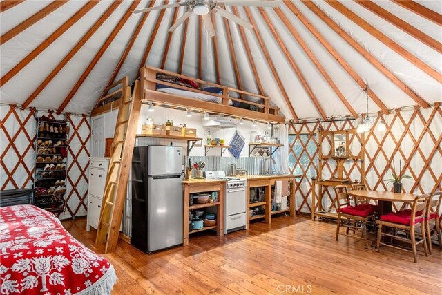 interior space with stainless steel fridge, hardwood / wood-style flooring, and lofted ceiling