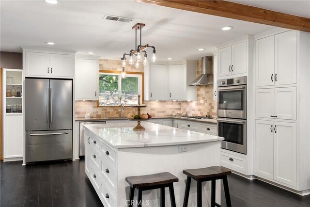 kitchen with a center island, wall chimney exhaust hood, stainless steel appliances, dark hardwood / wood-style floors, and white cabinets