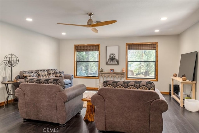 living room with dark wood finished floors, baseboards, a ceiling fan, and a healthy amount of sunlight