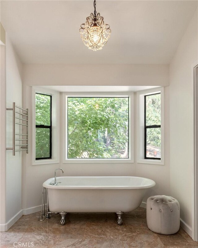 bathroom featuring a chandelier, radiator heating unit, a tub to relax in, and plenty of natural light