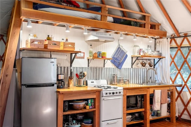 kitchen featuring black microwave, a sink, open shelves, white gas range oven, and freestanding refrigerator