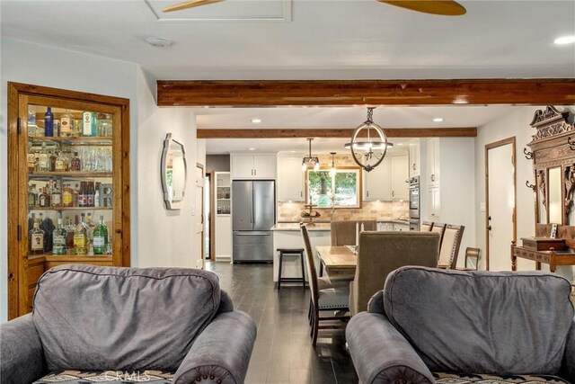 living room featuring dark hardwood / wood-style flooring, beamed ceiling, and a chandelier