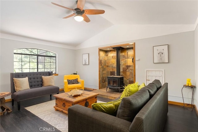 living area with lofted ceiling, a wood stove, baseboards, dark wood-style floors, and a ceiling fan