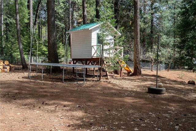 view of yard with a trampoline and a view of trees