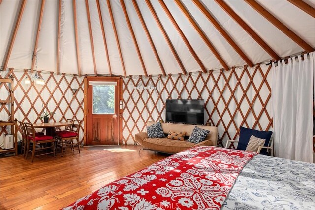 bedroom with vaulted ceiling with beams and light hardwood / wood-style flooring