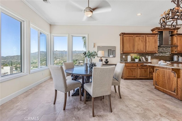 dining room featuring a mountain view, crown molding, and ceiling fan with notable chandelier